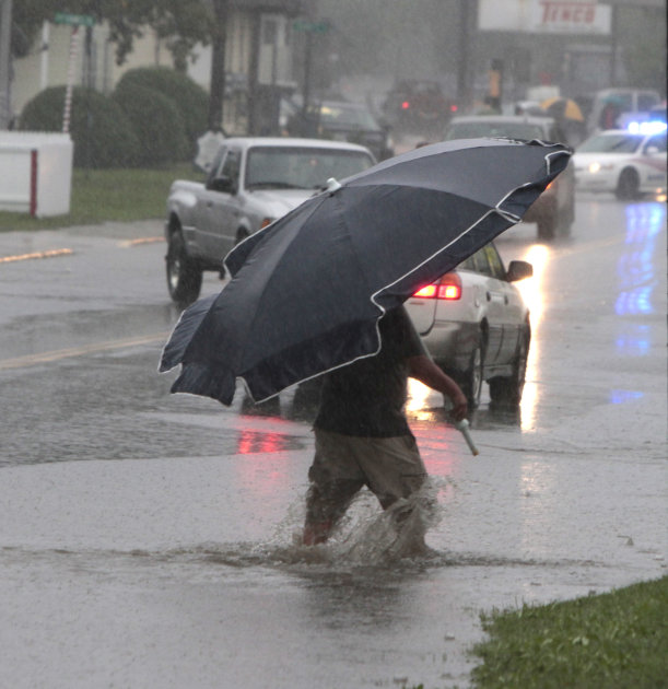 A pedestrian uses a beach umbrella to keep off the rain from tropical storm Irene on Sunday, Aug. 28, 2011 in Barre, Vt. Irene weakened to winds of 60 mph, well below the 74 mph dividing line between 