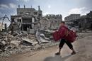 A Palestinian boy carries pillows as he passes by destroyed houses, during a 12-hour cease-fire in Gaza City's Shijaiyah neighborhood, Saturday, July 26, 2014. Gaza residents used a 12-hour humanitarian cease-fire on Saturday to stock up on supplies and survey the devastation from nearly three weeks of fighting, as they braced for a resumption of Israel's war on Hamas amid stalled efforts to secure a longer truce. (AP Photo/Khalil Hamra)