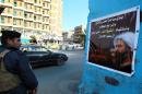 An Iraqi policeman guards a checkpoint in Baghdad on January 3, next to a poster mourning prominent Shiite cleric Nimr al-Nimr, who was executed by Saudi Arabia