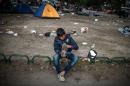 A boy checks his shoe at a park where migrants have found temporary shelter in the Serbian capital Belgrade on August 25, 2015