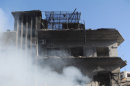 In this photo released by the Syrian official news agency SANA, Syrian army soldiers and security officers inspect the blast area in front of a damaged building of the air intelligence forces, which was attacked by one of two explosions, in Damascus, Syria, on Saturday, March 17, 2012. Two 
