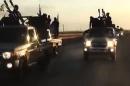 An image grab taken from a video released by the Islamic State group's official Al-Raqqa site via YouTube allegedly shows IS recruits riding in armed trucks in an unknown location