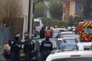 Police officers and firefighters stand next to a building in Toulouse, France, Wednesday, March 21, 2012 where a suspect in the shooting at he Ozar Hatorah Jewish school has been spotted. French police exchanged fire and were negotiating Wednesday with the gunman who claims connections to al-Qaida and is suspected of killing three Jewish schoolchildren, a rabbi and three paratroopers. (AP Photo/Remy de la Mauviniere)