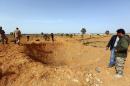 Members of Libya Dawn, a militia alliance that includes Islamists, surround a crater following a reported air raid by Libyan pro-government forces south-east of Tripoli in March