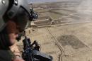 An Afghan soldier looks out from a helicopter over part of Paktika province, where the Pentagon says a senior Al-Qaeda commander was killed by a US air strike