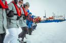 Passengers link arms and stamp out a helicopter landing site on the ice near the MV Akademik Shokalskiy (back R), still stuck in the ice off eastern Antarctica, as the ship waits for a possible helicopter rescue, December 31, 2013