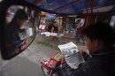A tuk tuk driver reads a story about elections near a newspaper stand in Phnom Penh