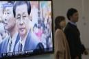 A couple walks past a television showing a report on Jang Song Thaek, North Korean leaders' uncle, at a railway station in Seoul