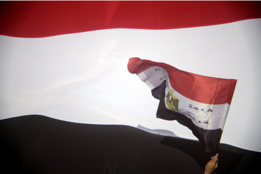 An Egyptian waves by Egypt's flag  at Tahrir Square, the focal point of Egyptian uprising, in Cairo, Egypt, Friday, July 8, 2011. Thousands of Egyptians took to the streets around the country Friday to demand justice for victims of Hosni Mubarak's regime and press the new, military rulers for a clear plan of transition to democracy. (AP Photo/Amr Nabil)