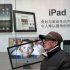 FILE - In this Jan. 26, 2011 file photo, a man stands near an advertisement for an Apple iPad  in Shanghai, China. News reports say more Chinese cities have seized iPads from retailers due to a dispute between Apple Inc. and a local company over ownership of the tablet computer's name. (AP Photo/Eugene Hoshiko, File)