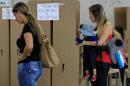 A woman carrying her daughter casts her vote in a referendum on a peace deal between the government and Revolutionary Armed Forces of Colombia (FARC) rebels in Medellin