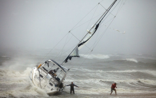 One of two people rescued from a sailboat, right, uses a line to make their way onto the beach on Willoughby Spit in Norfolk Saturday morning, Aug. 27, 2011 after they and another person were rescued from the boat that foundered in the waters of the Chesapeake Bay. A rescuer, left, waits for s second person to exit the boat. (AP Photo/TheVirginian-Pilot, Bill Tiernan)