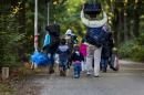 A small group of asylum seekers leave a camp set for thousands of migrants on October 2, 2015 in the village pavilion Heumensoord in Nijmegen, Netherlands