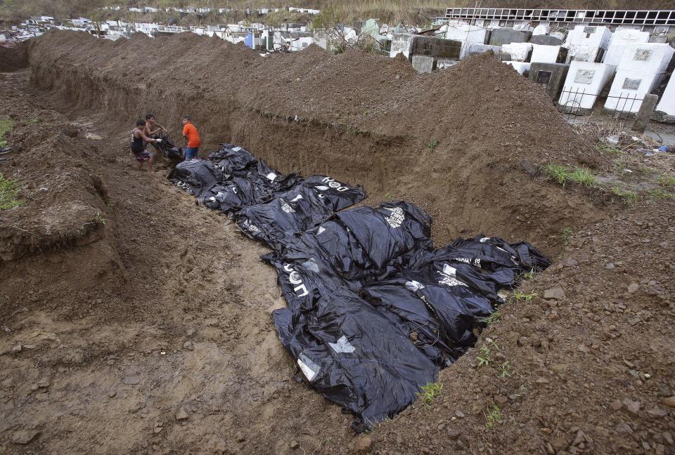 Workers arrange body bags at a mass burial site at the Basper public cemetery in Tacloban, Leyte province, central Philippines on Thursday, Nov. 14, 2013. Typhoon Haiyan, one of the strongest storms on record, slammed into 6 central Philippine islands on Friday leaving a wide swath of destruction. (AP Photo/Aaron Favila)