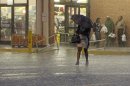 A woman walks through a heavy rain as others wait for the rain to stop at a grocery store in Montgomery, Ala., Monday, March 18, 2013. A line of severe thunderstorms crossed the state, bringing heavy rain and high winds. (AP Photo/Dave Martin)