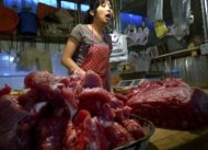 Seorang pedagang daging babi melayani pembeli di sebuah pasar kecil di Beijing, China.