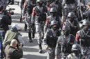 Riot policemen stand guard as protesters from the Islamic Action Front and other opposition parties demonstrate following an announcement that Jordan would raise fuel prices, including a hike on cooking gas, after Friday prayers in Amman