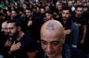 In this Saturday, Oct. 24, 2015 photo, a Lebanese Shiite supporter of Hezbollah with a tattoo on his head that reads in Arabic, "Oh Ali", beats his chest during the holy day of Ashoura, in the southern suburb of Beirut, Lebanon. A growing number of Shiite Muslims in Lebanon are getting tattoos with religious and other Shiite symbols since the civil war in neighboring Syria broke out five years ago, fanning sectarian flames across the region. (AP Photo/Hassan Ammar)