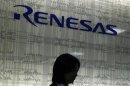 A receptionist is seated in front of a logo of Japanese chipmaker Renesas Electronics at the company headquarters in Tokyo