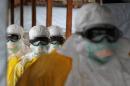 Health care workers, wearing protective suits, leave a high-risk area at the MSF-run Elwa hospital on August 30, 2014 in Monrovia