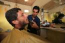 An Iraqi man has his beard shaved inside a barber shop in Intisar district of Mosul