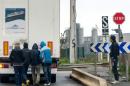 Immigrants wait behind a lorry at a stop sign in the northern French city of Calais, on October 24, 2014