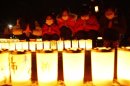 Girls pray after arranging candles at a candlelight event in Iwaki