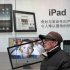 FILE - In this file photo taken on Jan. 26, 2011, a man stands near Apple's iPad advertisement in Shanghai, China.  The official said Monday, Feb. 13, 2012,  that investigators in Shijiazhuang, southwest of Beijing, started seizing iPads last week at the request of a company that filed a complaint with the government accusing Apple Inc. of violating its rights to the iPad name.  (AP Photo/Eugene Hoshiko, File)