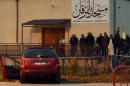 People stand near a car in Valence, France, on January 1, 2016, after a soldier guarding the mosque shot and wounded its driver