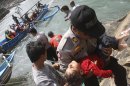 A police officer carries a child who appears to be unconscious after a boat carrying asylum seekers sank off Java island, in Cianjur, West Java, Indonesia, Wednesday, July 24, 2013. Rescuers were searching Wednesday for dozens of asylum seekers still believed missing after their boat sank in Indonesian waters on the way to Australia. More than 150 survivors were brought to safety and three bodies were recovered. (AP Photo)