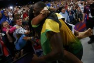 A fan hugs Jamaica's Usain Bolt (R) after his team set a new world record of 36.84 seconds in the men's 4x100m relay final during the London 2012 Olympic Games at the Olympic Stadium August 11, 2012.  REUTERS/Kai Pfaffenbach (BRITAIN  - Tags: OLYMPICS SPORT ATHLETICS)