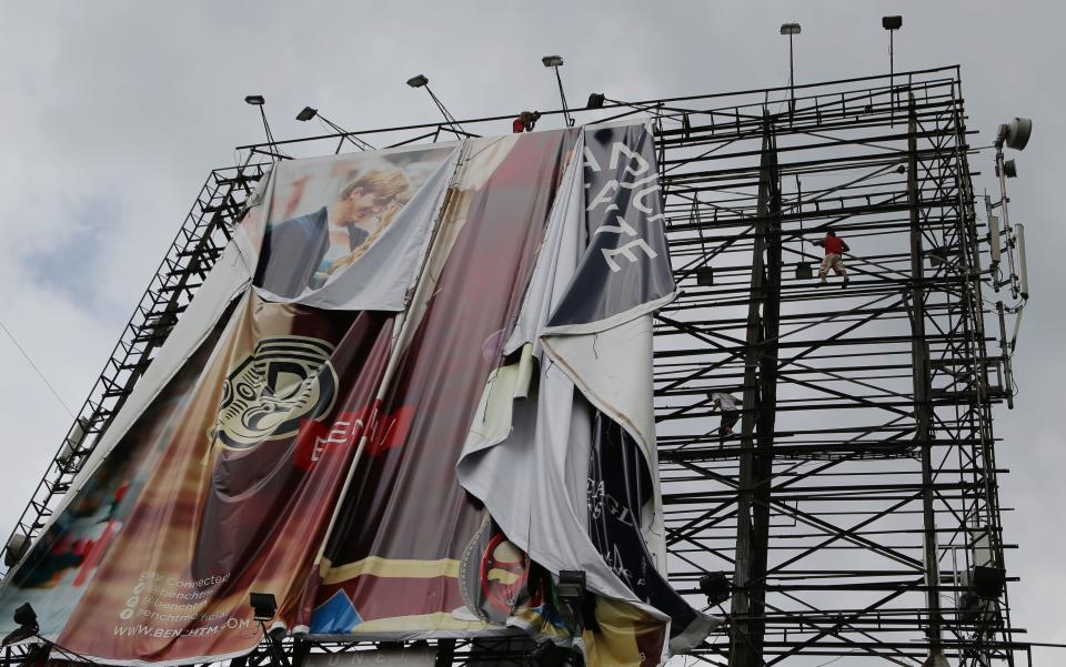 Filipino workers bring down a giant billboard along a busy highway as they prepare for the possible effects of powerful Typhoon Haiyan in suburban Makati, south of Manila, Philippines Thursday, Nov. 7, 2013. Philippine officials say thousands of villagers, including those from a central province devastated recently by an earthquake, are being evacuated ahead of the arrival of one of Asia's most powerful typhoons this year. (AP Photo/Aaron Favila)