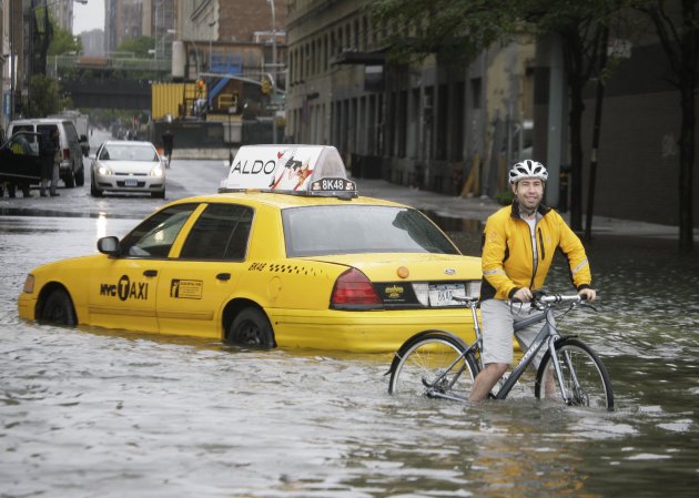A bicyclist makes his way past a stranded taxi on a flooded New York City Street as Tropical Storm Irene passes through the city, Sunday, Aug. 28, 2011. Although downgraded from a hurricane to a tropi