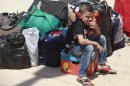 A Syrian refugee boy sits beside bags as he arrived at the border crossing by the Iraqi town of Qaim, 200 miles (320 kilometers) west of Baghdad, Iraq, Tuesday, Aug. 7, 2012. (AP Photo/Hadi Mizban)