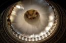 Sunlight streams into the interior of the U.S. Capitol dome, covered in tarps for repairs, and is seen from the Rotunda in Washington