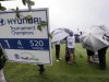 Players and their caddies stand under umbrellas as they wait to tee off in the first round at the Tournament of Champions golf tournament on Friday, Jan. 4, 2013, in Kapalua, Hawaii. (AP Photo/Elaine Thompson)