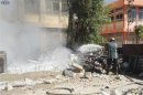 A firefighter uses a hose to spray water after bombs exploded in a school building in Damascus