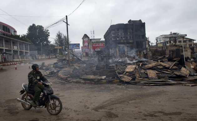 A man rides a motorcycle near a burned building that housed an orphanage for Muslim children in Lashio, northern Shan State, Myanmar, Thursday, May 30, 2013. Many Buddhists and Muslims stayed locked inside their homes and shops were shuttered after two-days of violence in Lashio town, near the border with China, the latest region to fall prey to the country's spreading sectarian violence. (AP Photo/Gemunu Amarasinghe)