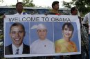 People holding a poster with portraits of U.S. President Barack Obama, left, Myanmar President Thein Sein, center, and Myanmar opposition leader and Nobel laureate Aung San Suu Kyi as they wait to welcome the arrival of U.S. President Barack Obama at Yangon International Airport Monday, Nov. 19, 2012, in Yangon, Myanmar. (AP Photo/Khin Maung Win)