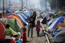 Migrants walk on a railway track at a makeshift camp on the Greek-Macedonian border, near the village of Idomeni