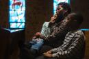 Church goer Pam Minner holds her daughter Mackinzy on her lap with her son Merrimon as they listen to a Thanksgiving service that discussed the communities reaction to ongoing protests in reaction to the grand jury verdict in the Michael Brown shooting in