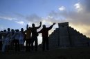 People gesture toward the the Kukulkan temple in Chichen Itza, Mexico, Friday, Dec. 21, 2012. Ceremonial fires burned and conches sounded off as dawn broke over the steps of the main pyramid at the Mayan ruins of Chichen Itza Friday, making what many believe is the conclusion of a vast, 5,125-year cycle in the Mayan calendar. Some have interpreted the prophetic moment as the end of the world. The hundreds gathered in the ancient Mayan city, however, said they believed it marked the birth of a new and better age. (AP Photo/Israel Leal)