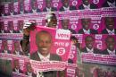 A supporter of presidential candidate Jovenel Moise holds up a campaign poster as he celebrates his candidate's victory in Petion-Ville, Haiti, Tuesday, Jan. 3, 2017. An electoral tribunal certified on Tuesday the presidential election victory of the first-time candidate. He will be sworn in on Feb. 7. (AP Photo/Dieu Nalio Chery)