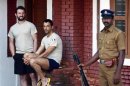 Girone and Massimiliano members of the navy security team of Italian merchant vessel Enrica Lexie are seen at the lawns of a guest house as a policeman stands guard in Kochi