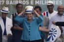 Brazil's President Dilma Rousseff, center, puts a hat during the inauguration of the BRT Transcarioca (Rapid Transit Bus) in Rio de Janeiro, Brazil, Sunday, June 1, 2014. The corridor has 39 kilometers long, cutting through 27 neighborhoods and will serve 320 thousand people every day, reducing in 60 per cent the average time of the commute. The corridor will connect the International Airport to the subway, which takes the passengers to the Maracana stadium. (AP Photo/Silvia Izquierdo)