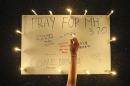 A woman places lighted candle on poster with messages expressing hope for passengers of missing Malaysia Airlines plane MH370 during a candlelight vigil in Petaling Jaya