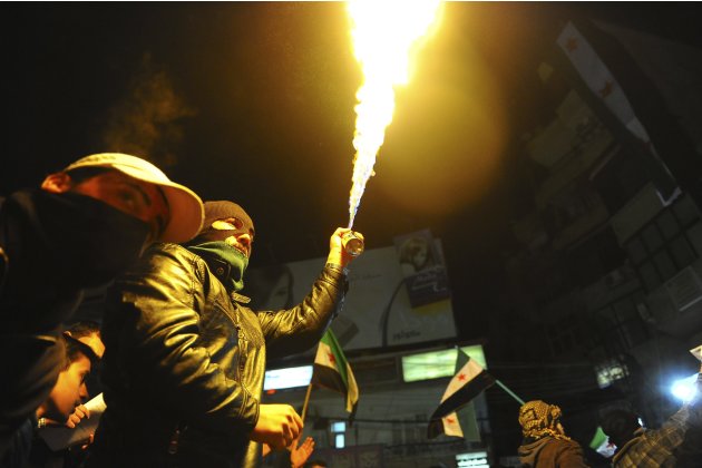 A demonstrator ignites an aerosol spray to create fire during a protest against Syria's President Bashar al-Assad in Qudsaya, near Damascus