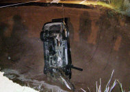 This image provided by the Utah Highway Patrol shows the wreckage of a car that ran into a hole, after heavy rain caused the collapse of State Road 35 that opened up a hole 40 feet wide and more than 30 feet deep. A teenage girl is dead and her father seriously injured after this SUV plunged into a hole in the highway near Tabiona, Utah early Thursday July 14, 2011. (AP Photo/Utah Highway Patrol)