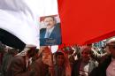 A young supporter of Yemen's former president Ali Abdullah Saleh holds a portrait of him under a giant national flag during a rally on November 7, 2014 in Tahrir Square in the capital Sanaa