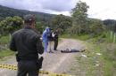 In this photo taken Wednesday, April 23, 2014, police officers and forensics look at the body of British citizen Henry Miller, 19, on a road outside Mocoa, in Colombia's southwestern state of Putumayo. Miller died after he drank a hallucinogen during a tribal ritual, his body left by the side of the road by two frightened young local men, said Saturday local police commander Ricardo Suarez. (AP Photo/Jose Horacio Villarreal)
